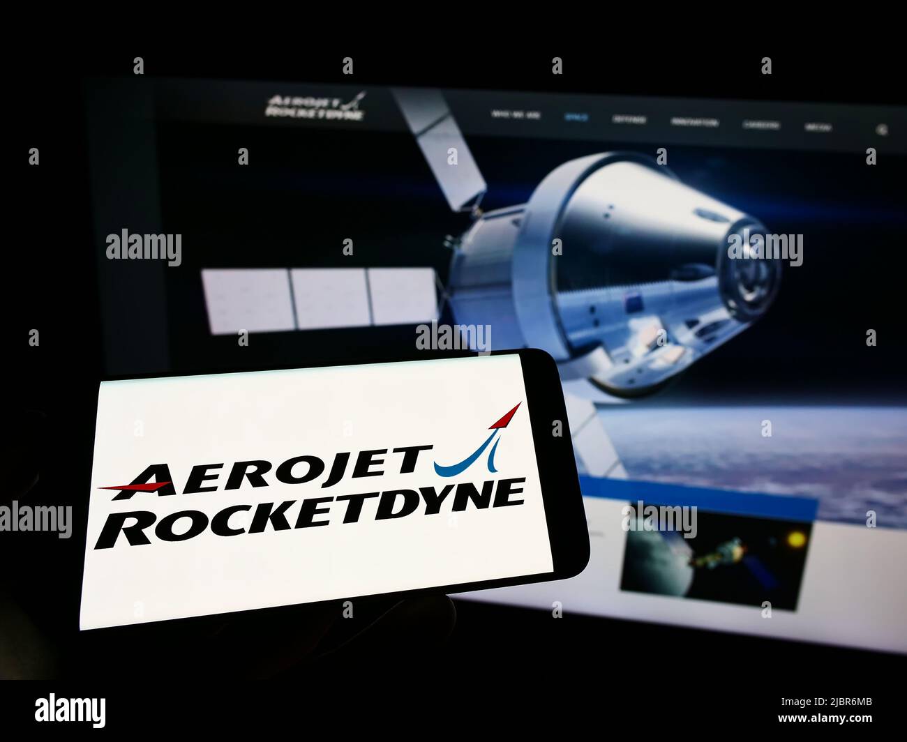 Persona che tiene il telefono cellulare con il logo della società aerospaziale americana Aerojet Rocketdyne sullo schermo di fronte alla pagina web. Mettere a fuoco sul display del telefono. Foto Stock
