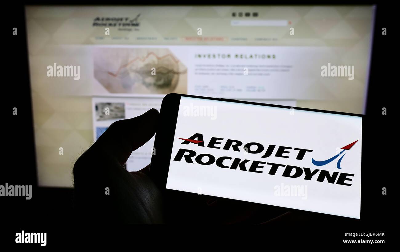 Persona che tiene il cellulare con il logo della società aerospaziale statunitense Aerojet Rocketdyne sullo schermo di fronte al sito web aziendale. Mettere a fuoco sul display del telefono. Foto Stock
