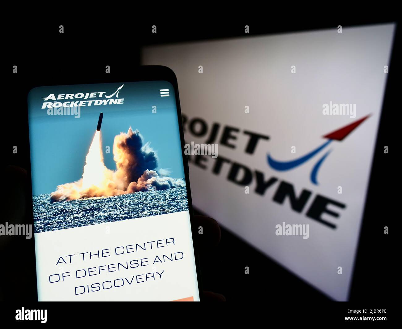 Persona che detiene il cellulare con il sito web della società aerospaziale statunitense Aerojet Rocketdyne sullo schermo di fronte al logo. Concentrarsi sul centro del display del telefono. Foto Stock