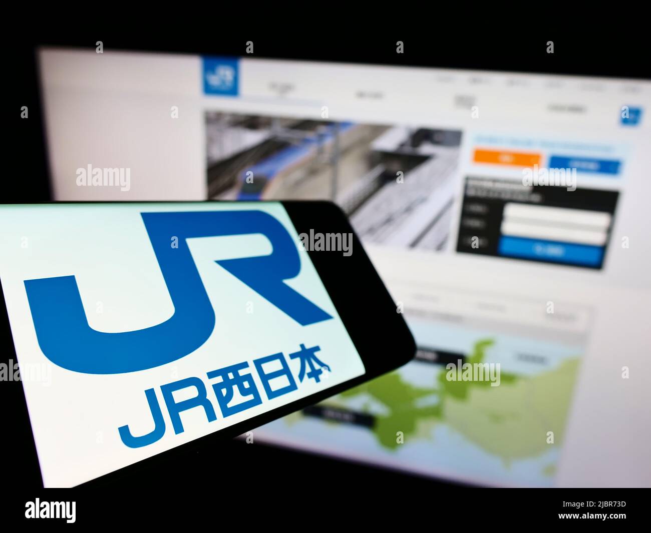 Cellulare con logo della compagnia giapponese West Japan Railway (JR) sullo schermo di fronte al sito web aziendale. Mettere a fuoco sulla sinistra del display del telefono. Foto Stock