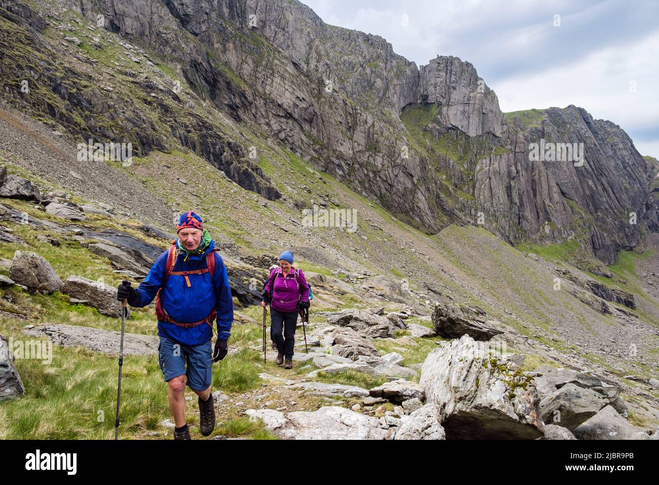 Escursionisti sul sentiero sotto Clogwyn Du'r Arddu Crags in CWM Brwynog sulle pendici del Monte Snowdon in montagne del Parco Nazionale di Snowdonia, Gwynedd, Galles del Nord Foto Stock