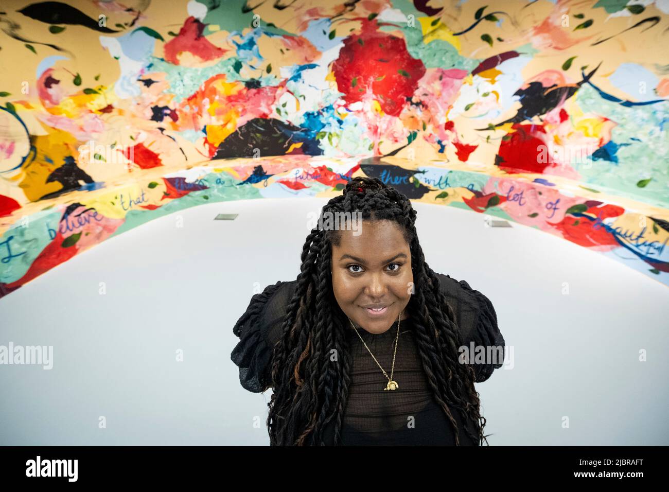 Londra, Regno Unito. 8 giugno 2022. La pittrice Michaela Yearwood-Dan pone con il suo lavoro “Let Me Hold You”, un murale curvo, in mostra presso lo spazio permanente di arti aperto di recente per artisti e comunità LGBTQ+ a Queercircle a North Greenwich. Credit: Stephen Chung / Alamy Live News Foto Stock