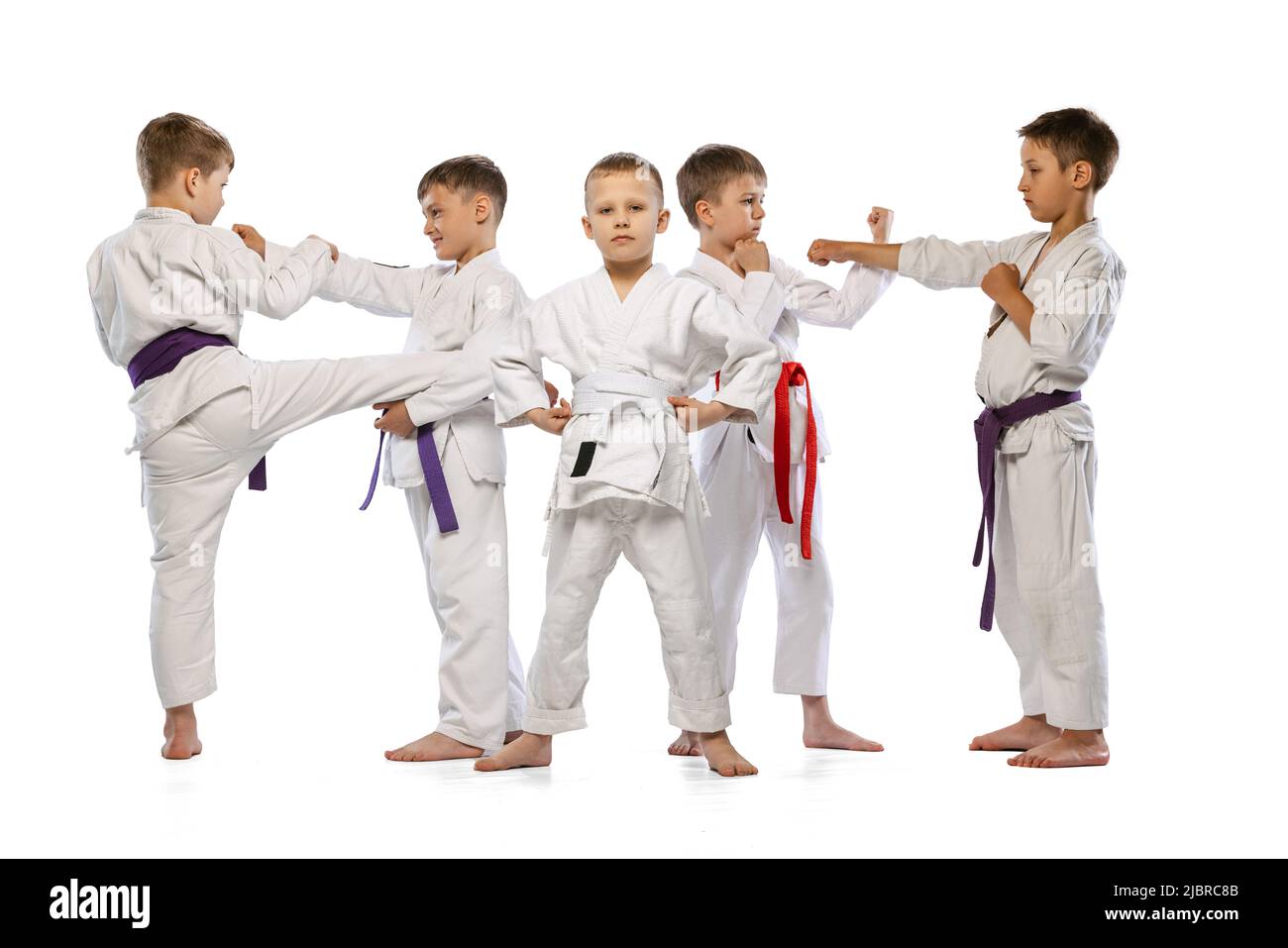 Gruppo di bambini felici, combattenti per il karate principiante in picchietti bianchi che si ergono insieme isolati su sfondo bianco. Concetto di sport, arti marziali Foto Stock