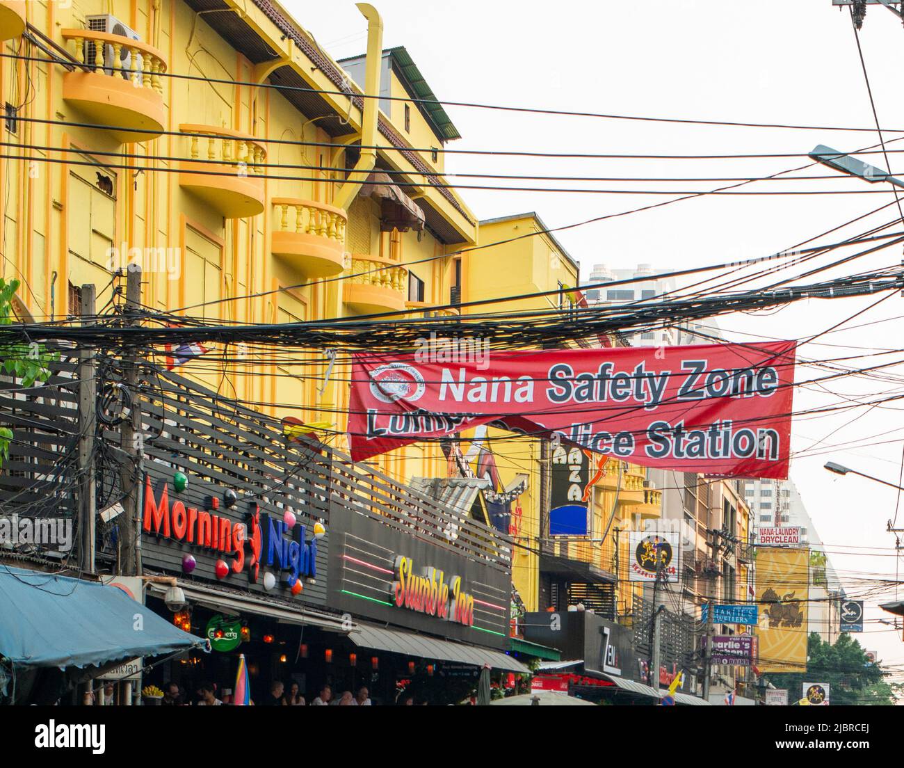 Banner che pubblicizza la sicurezza una stazione di polizia per Nana Plaza, Bangkok, tra i cavi telefonici e l'alimentazione. Foto Stock