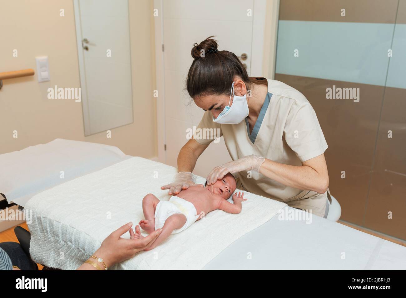 Fisioterapista femminile che esegue una fascia cervicale superficiale in un neonato. Foto Stock