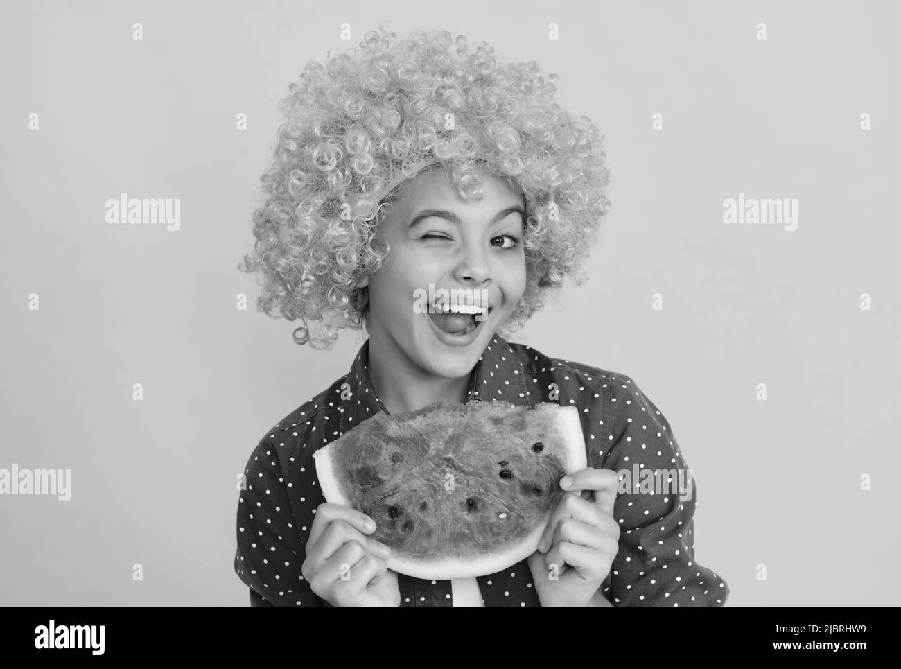 d'estate. il bambino che vinza con i capelli arancioni tiene la fetta di melone dell'acqua. il cocomero succoso di yummy Foto Stock