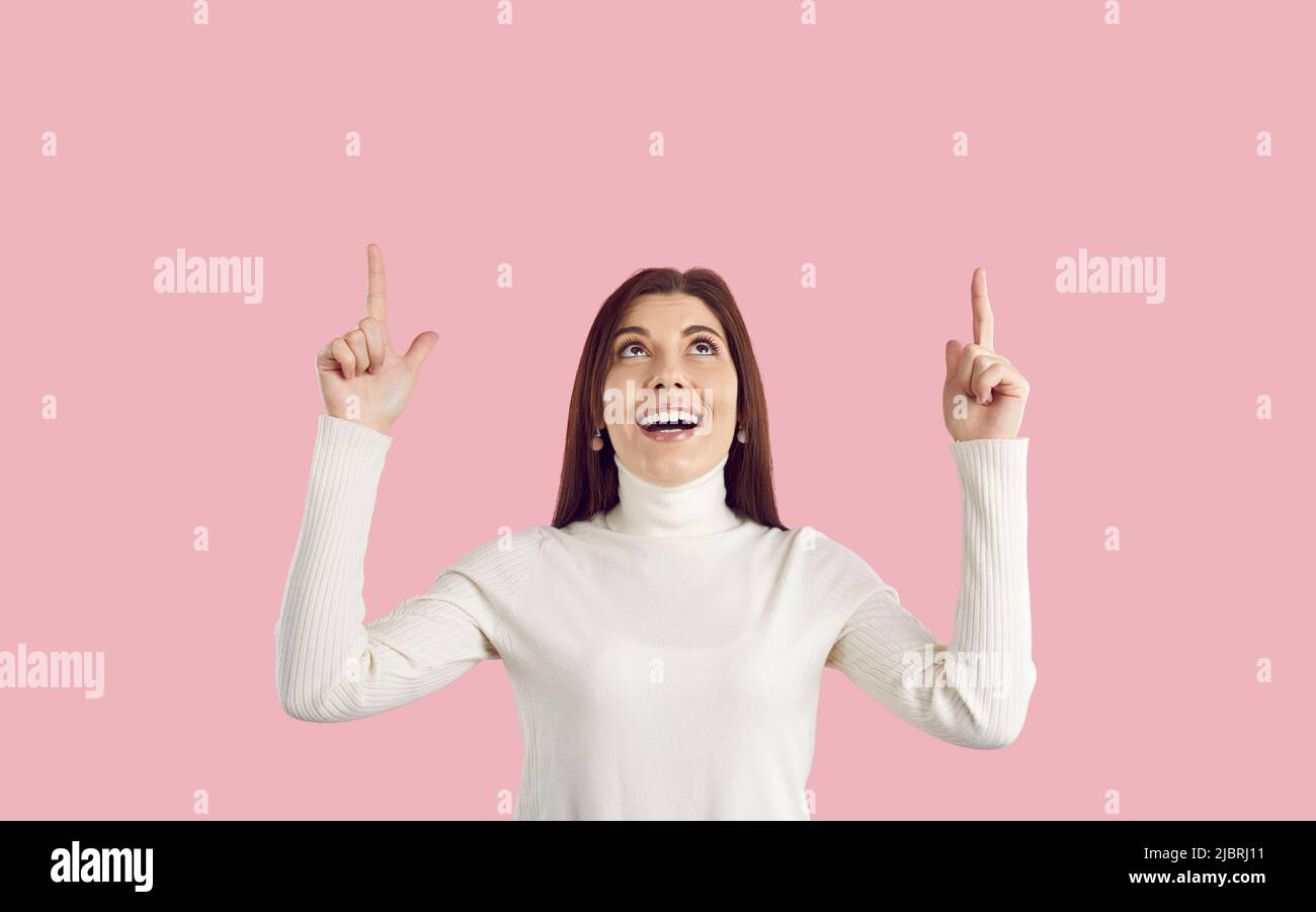 Donna felice su sfondo rosa pubblicità sconti, puntando a spazio copia e sorridente Foto Stock