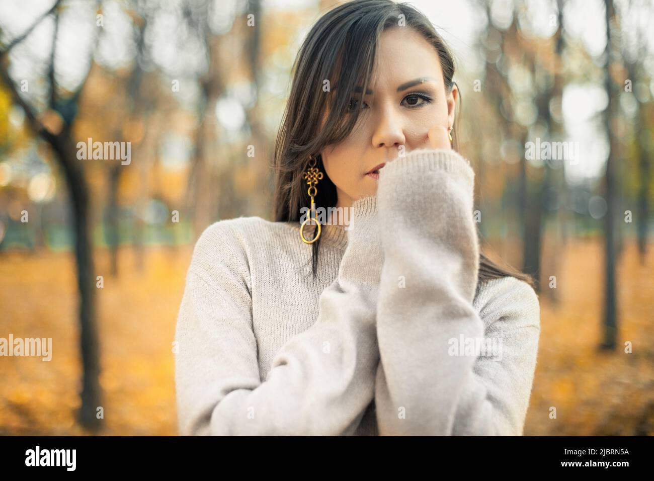 Ritratto di una bella donna asiatica che cammina all'aperto. Bella donna in un maglione. Ritratto di moda di bella donna elegante all'aperto Foto Stock