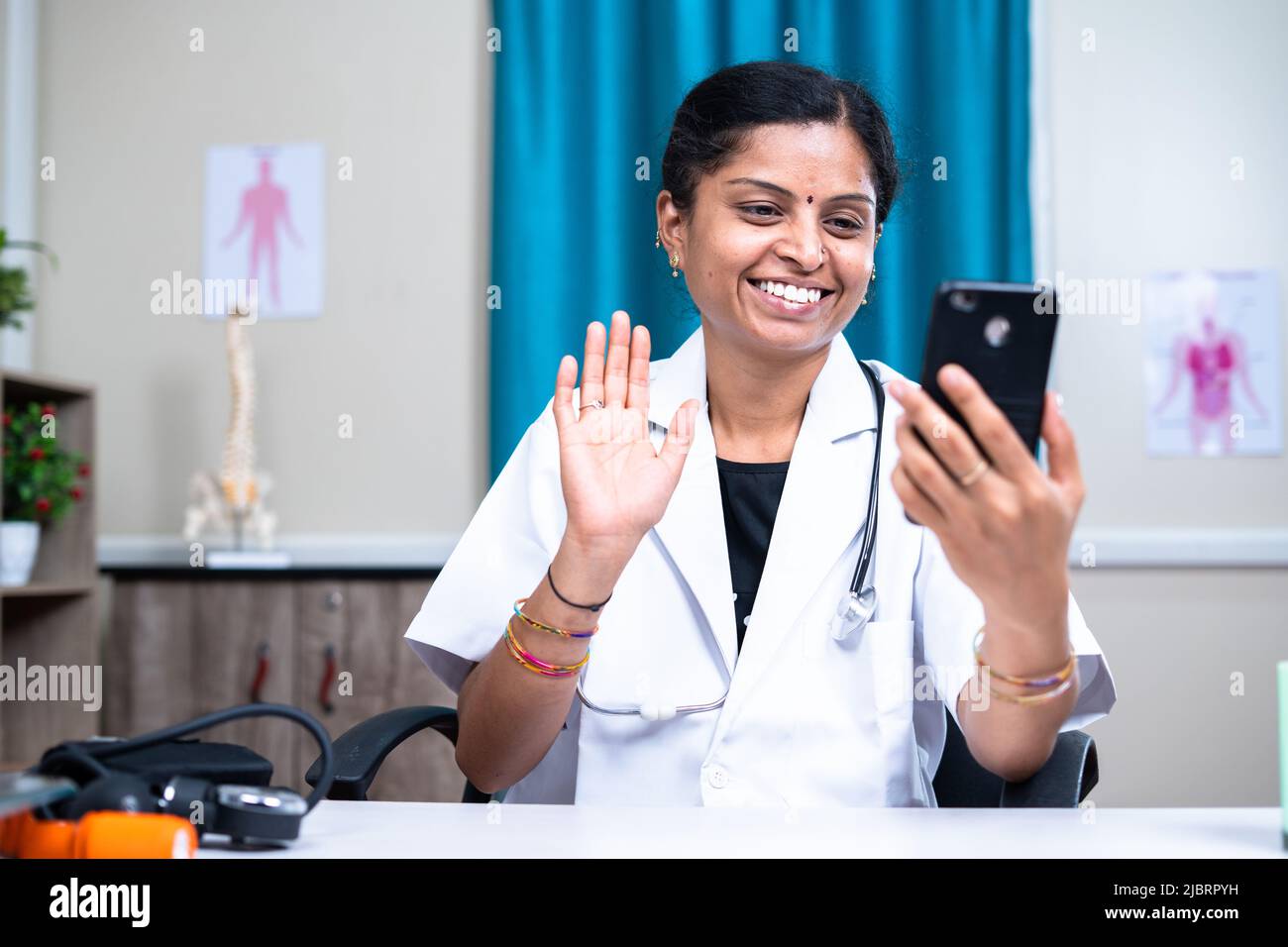 Donna Dottore in videochiamata con il paziente sul telefono cellulare in ospedale - concetto di salute, consulenza medica visruale e tecnologia Foto Stock