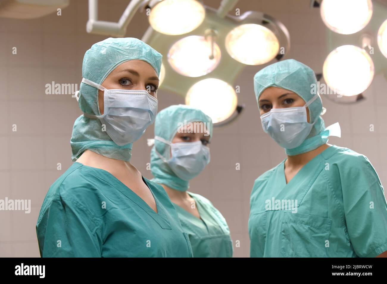 Tre infermieri sono visti in una sala operatoria chirurgica. Sono vestiti  come un'infermiere di teatro di operazione con le maschere facciali e  vestiti chirurgici sterili Foto stock - Alamy