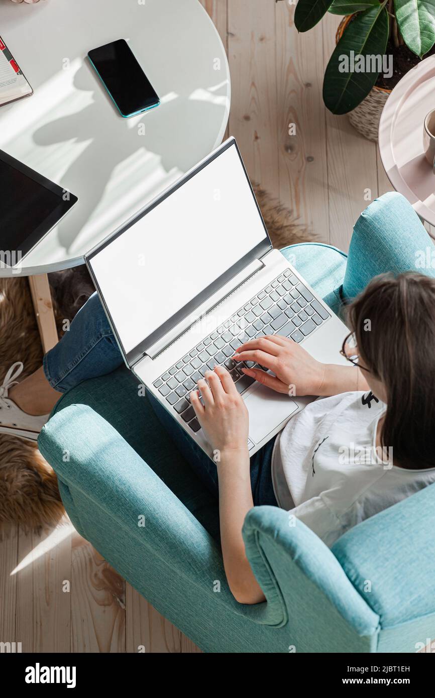 Giovane donna che usa lo schermo del laptop vuoto, mock-up, lavoro a casa, vista dall'alto Foto Stock