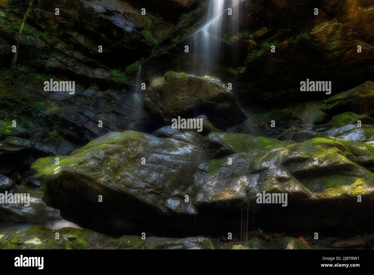 Il primo piano di una piccola insenatura che cade su una scogliera di rocce e bounders con soleggiate penatra l'area ombreggiata. Foto Stock