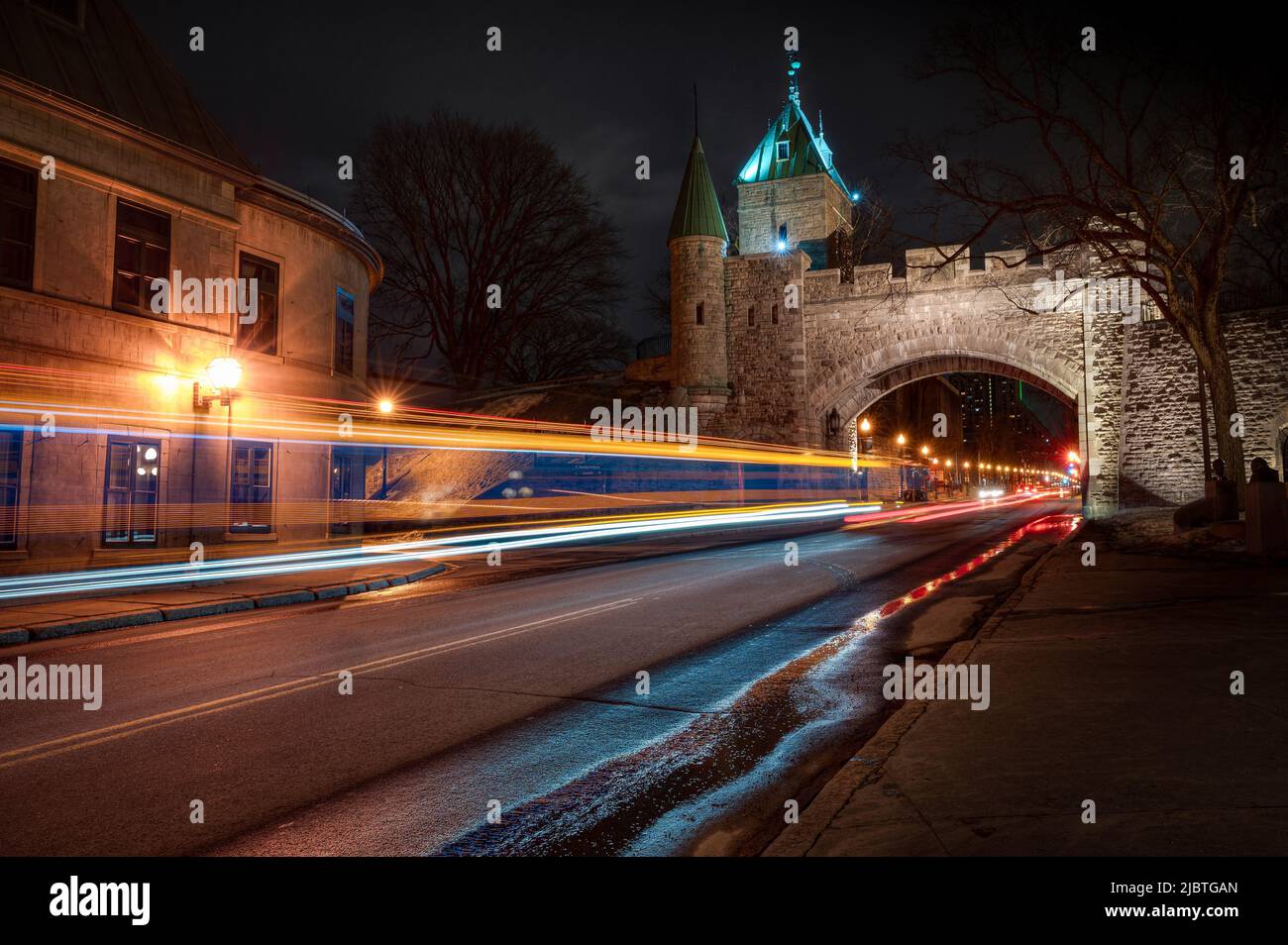 Porta St-Louis, arco nelle fortificazioni della città di Quebec di notte, mentre auto e autobus sono di passaggio, QC, Canada Foto Stock