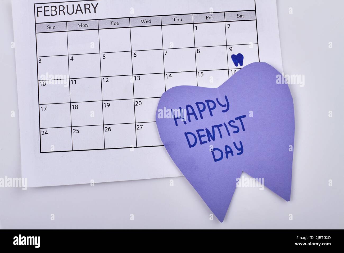 Buon giorno dentisti. Febbraio 9 segnare sul primo piano del calendario. Cartone a forma di dente con testo. Foto Stock