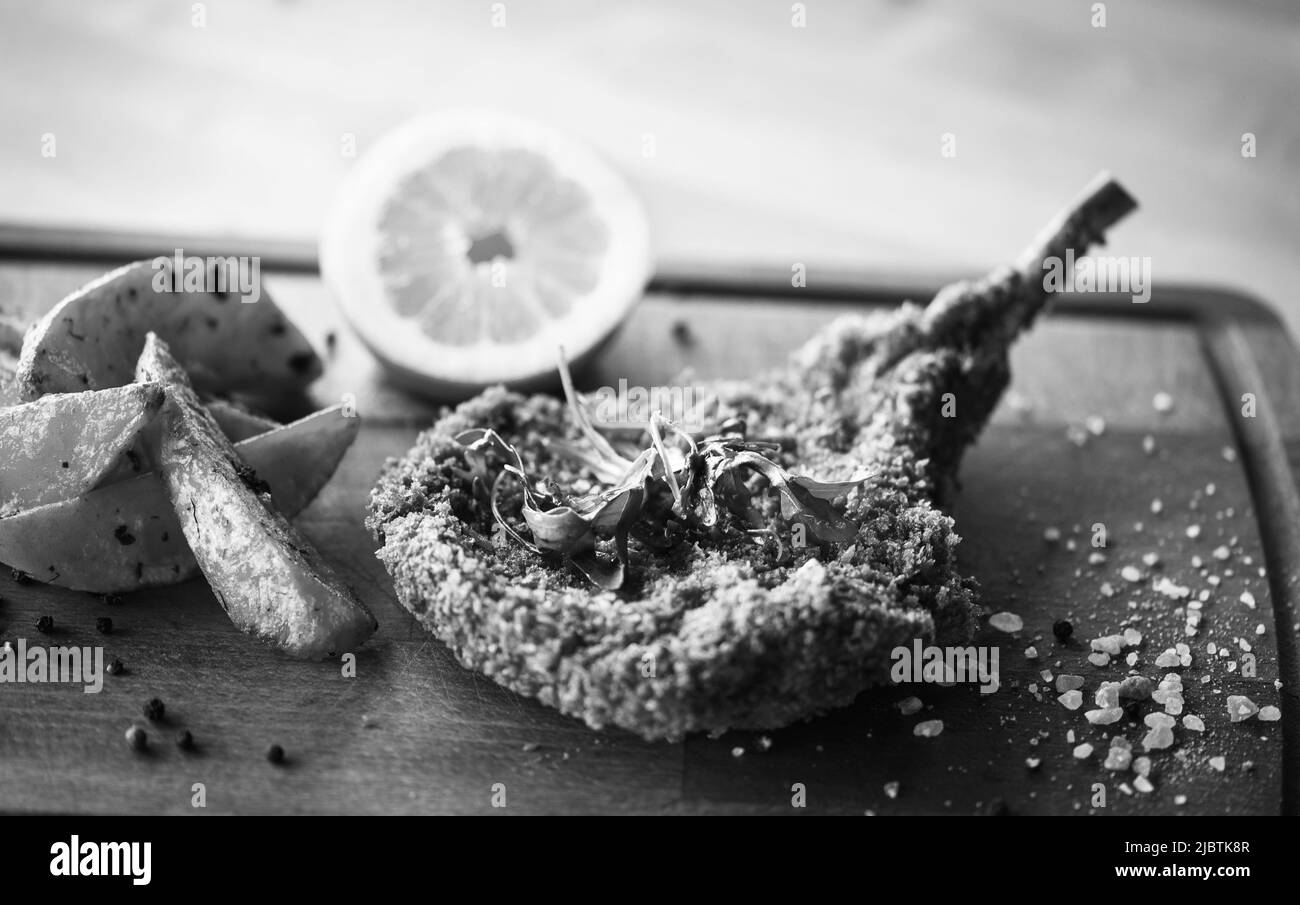 delizioso scnitzel di maiale panko croccante con spicchi e pepe fresco Foto Stock