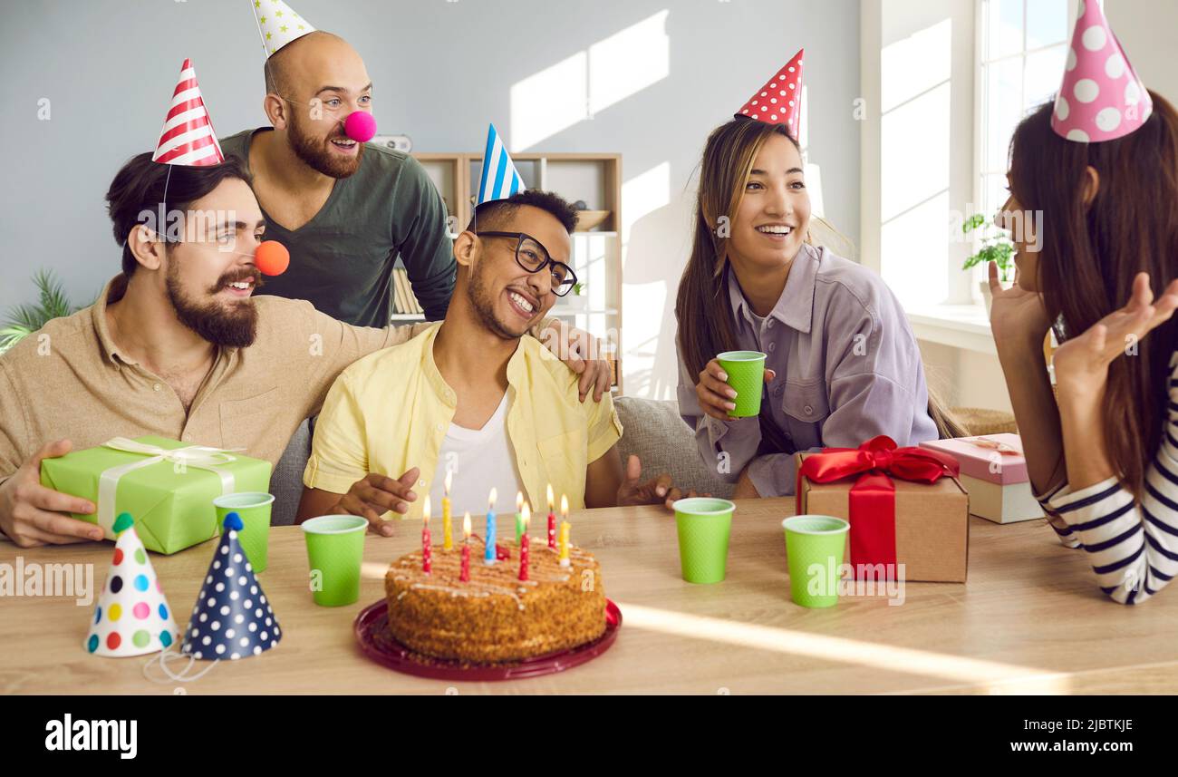 Amici felici e diversi festeggiano il compleanno con la torta Foto Stock