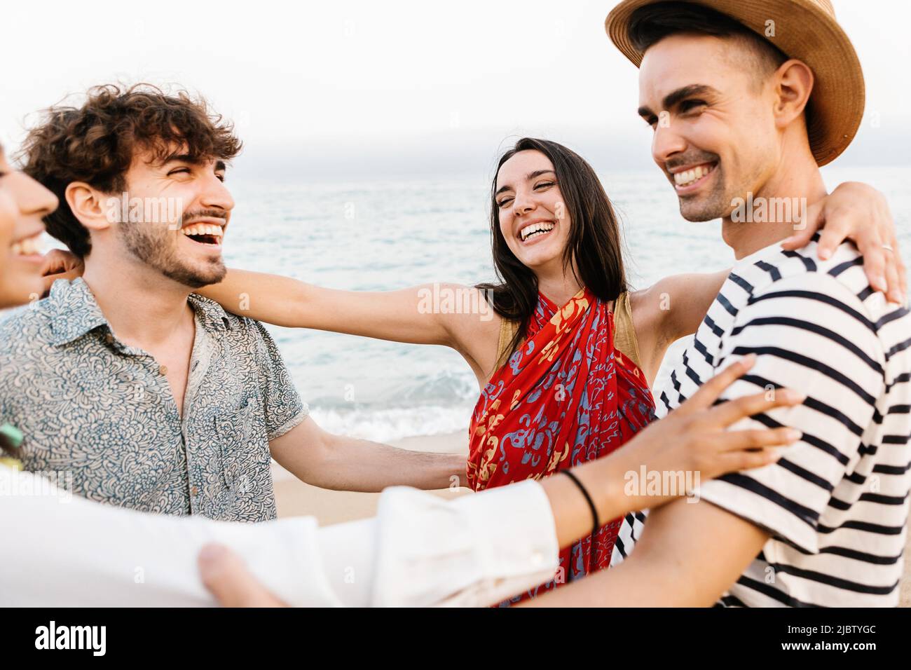Gruppo di giovani amici felici che ridono insieme mentre si diverte sulla spiaggia Foto Stock