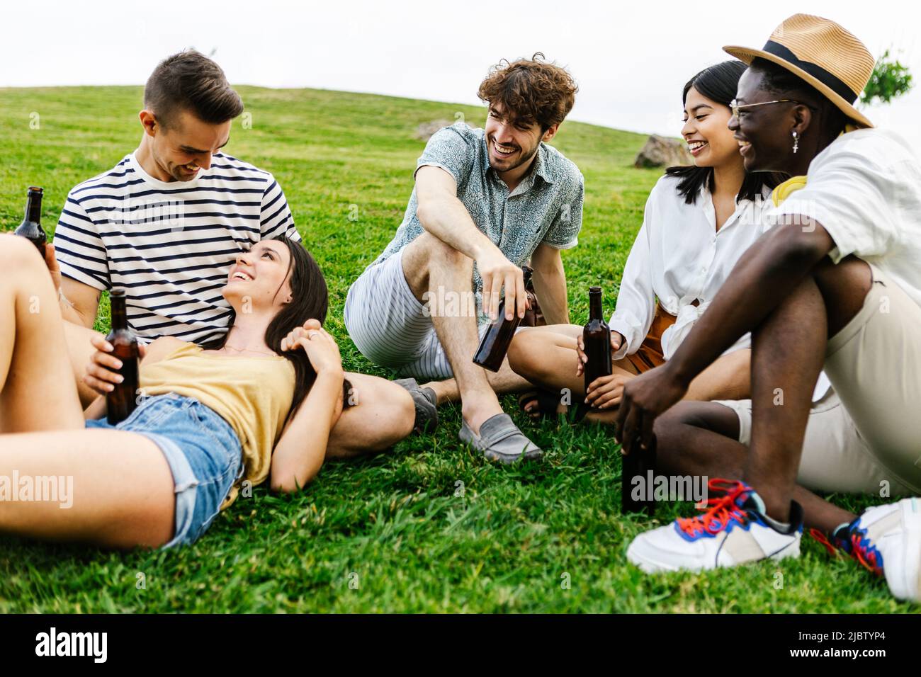 Gruppo di amici multirazziali che si aggrappano e parlano all'aperto nel parco pubblico Foto Stock