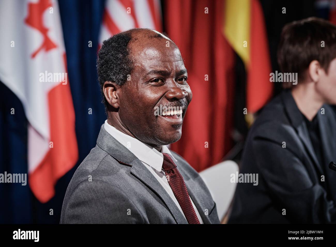 Un politico afroamericano in completo ridere mentre siede all'incontro internazionale con i colleghi Foto Stock