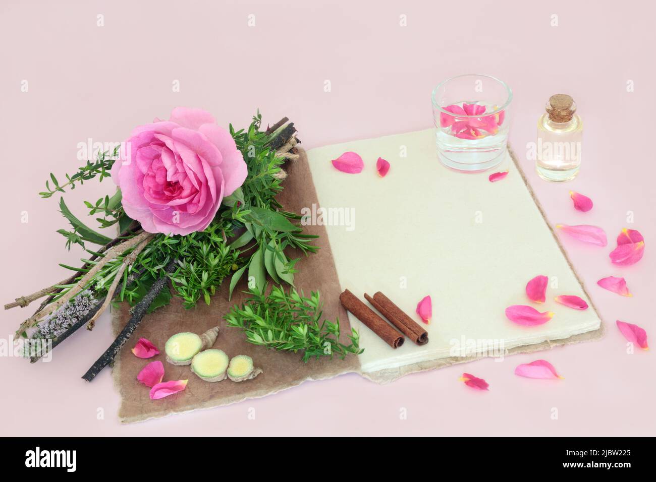 Streghe amore pozione ricetta incantesimo con fiore di rosa, bundle erbe, quarzo cristallo, acqua di sorgente, canapa ricetta notebook, bottiglia d'olio, zenzero e cannella. Foto Stock