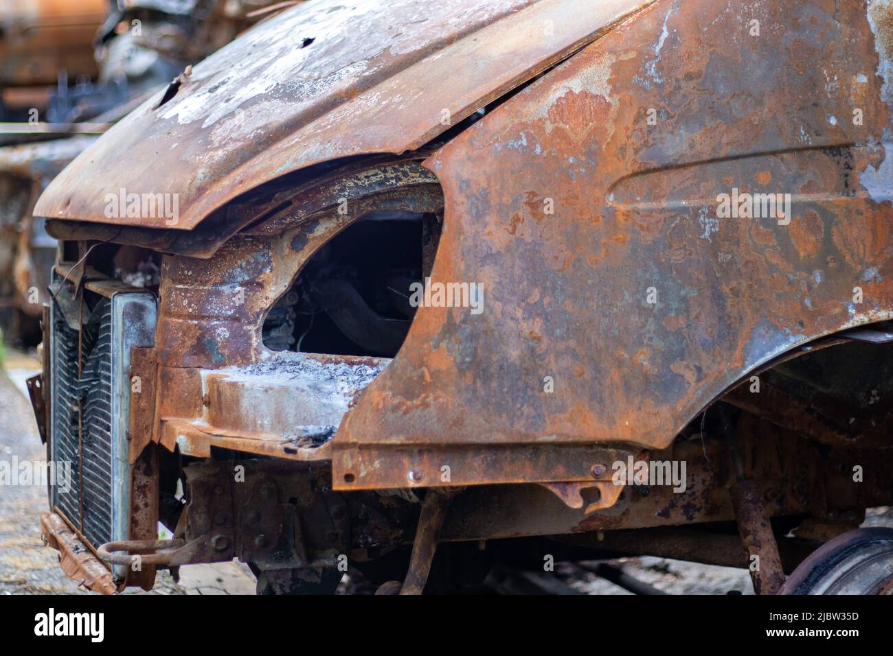 L'auto è stata completamente distrutta da un incendio. Auto abbandonata, bruciata e arrugginita sulla strada. Le automobili erano incendiate nel parcheggio. Guerra della Russia contro Ukra Foto Stock