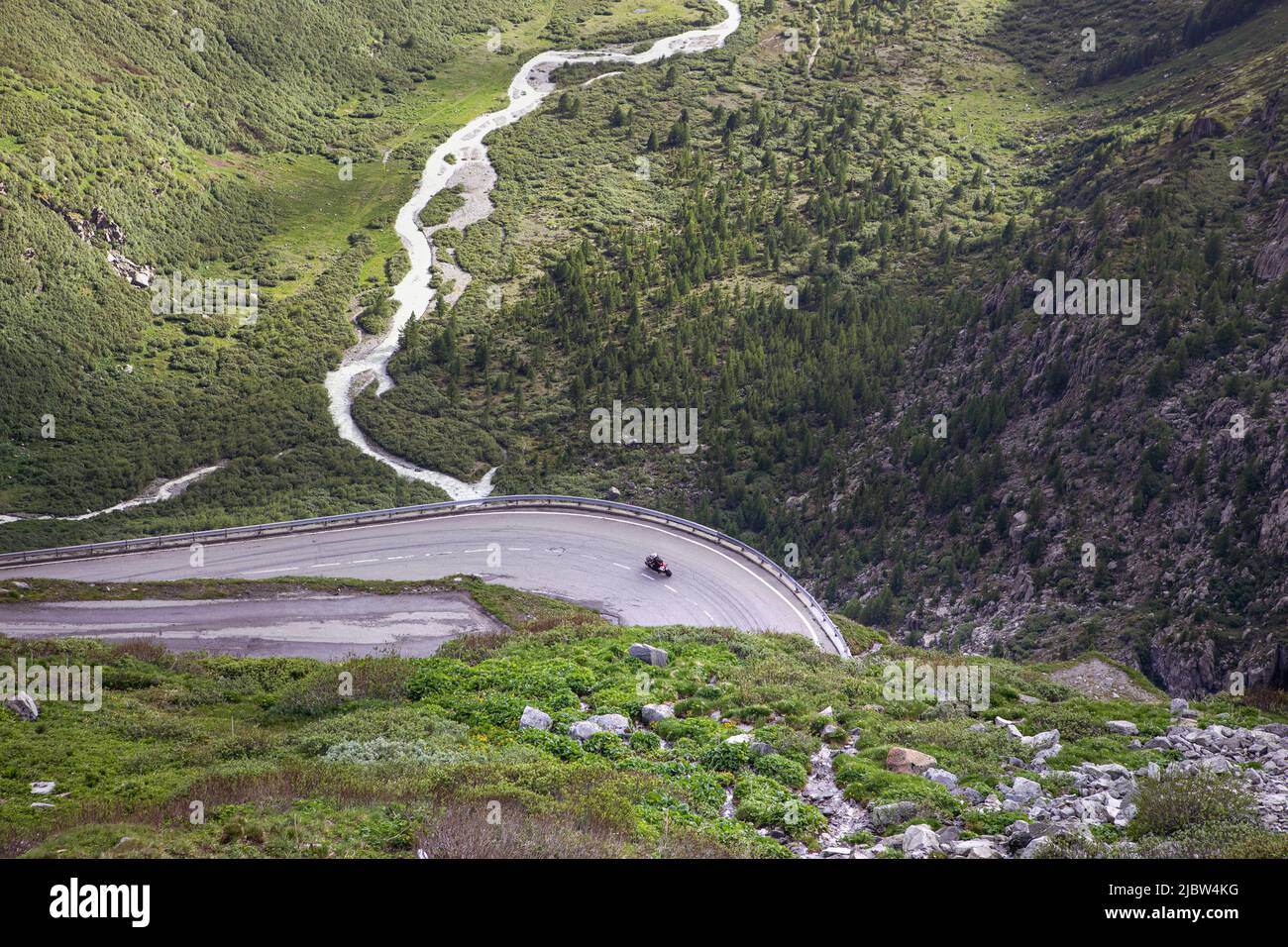 Vista sulla strada a serpentina sul passo di montagna e sul bellissimo paesaggio alpino. Moto driver su una curva dall'alto con verde valle estiva del fiume. F Foto Stock