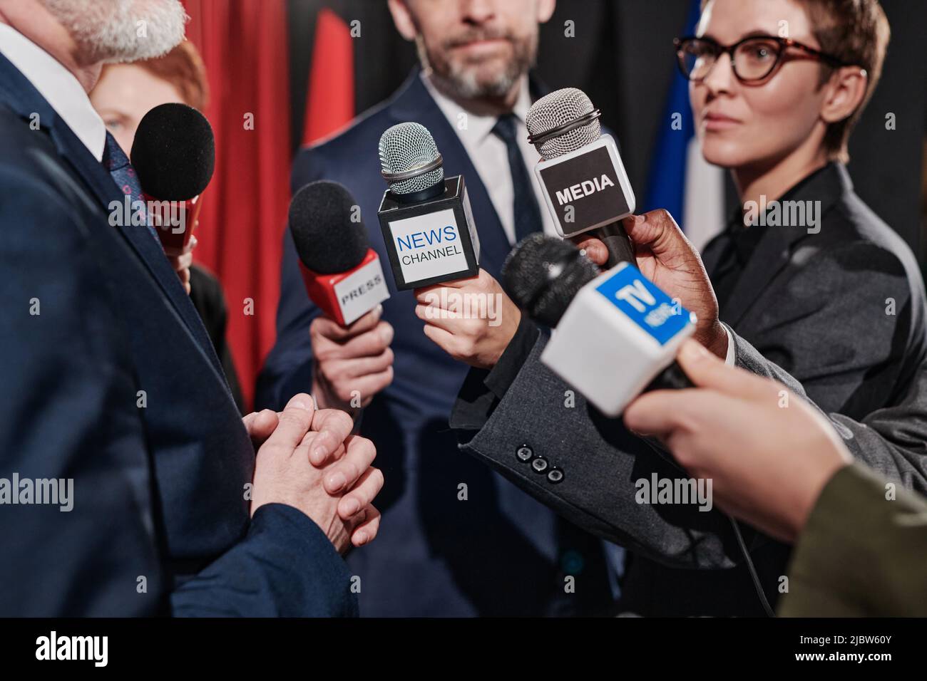 Primo piano di un gruppo di giornalisti che tengono microfoni davanti all'uomo d'affari e lo intervistano alla conferenza Foto Stock