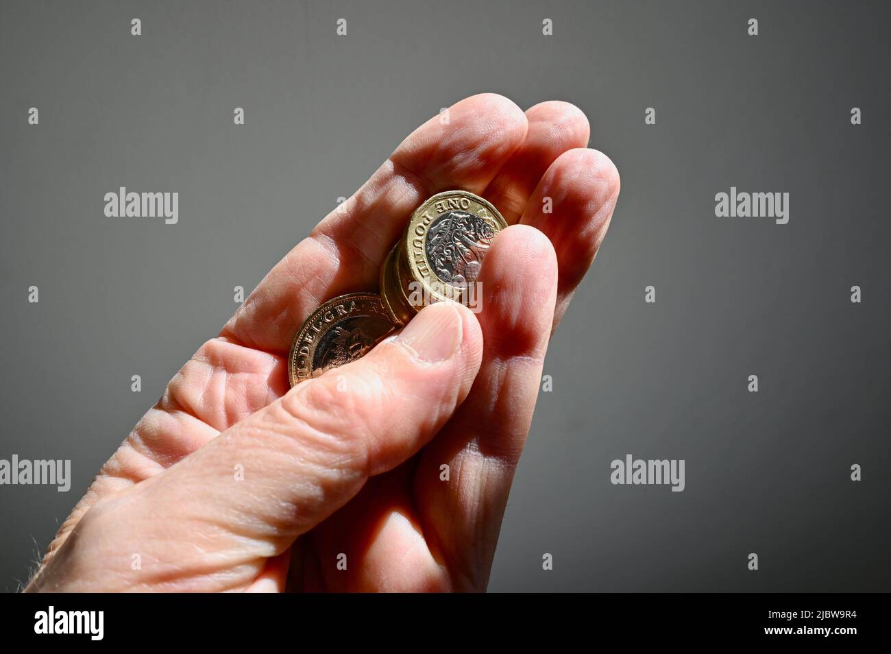 Primo piano delle monete in sterline britanniche tenute in mano a una persona anziana. Foto Stock