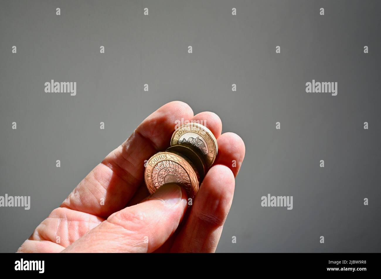 Primo piano delle monete in sterline britanniche tenute in mano a una persona anziana. Foto Stock