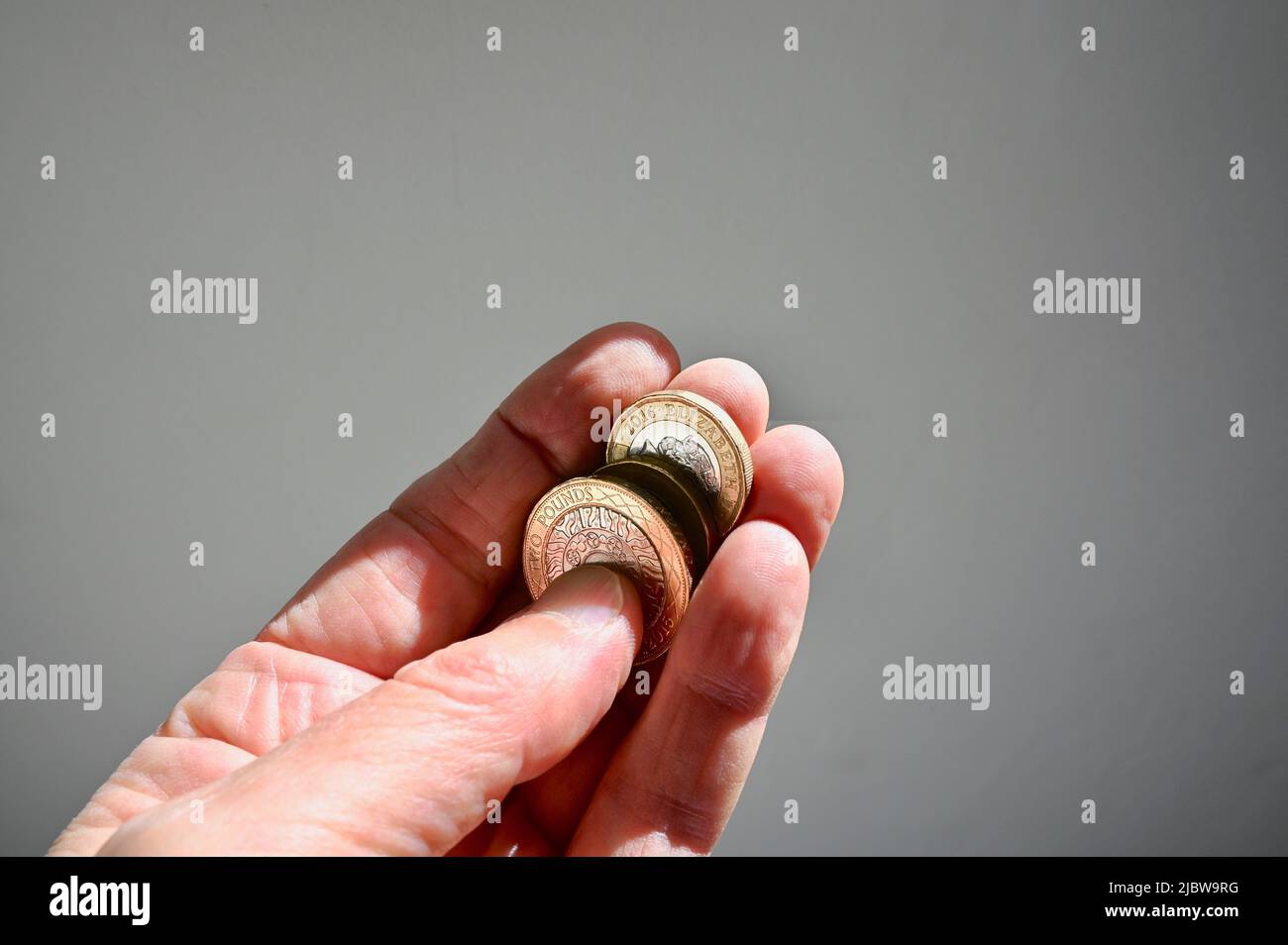 Primo piano delle monete in sterline britanniche tenute in mano a una persona anziana. Foto Stock