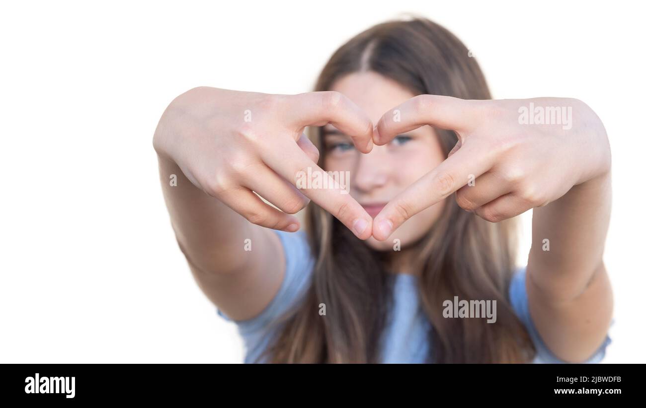 Fuoco selettivo delle mani di una giovane ragazza che forma un cuore con le sue dita su sfondo bianco. Gesto ed espressione dell'amore Foto Stock
