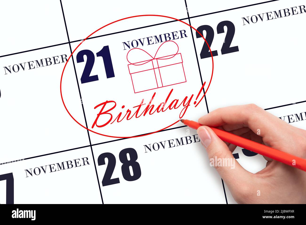 21st novembre. La mano cerchia la data sul calendario 21 novembre, disegna una scatola regalo e scrive il testo compleanno. Vacanza. Autunno mese, giorno Foto Stock