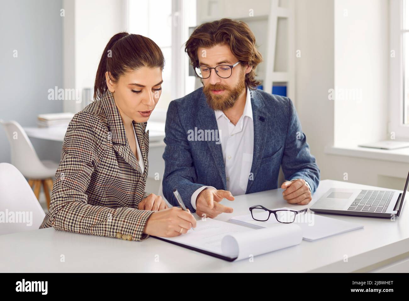 Due colleghi maschi e femmine lavorano insieme su un progetto aziendale congiunto e ne discutono in ufficio. Foto Stock