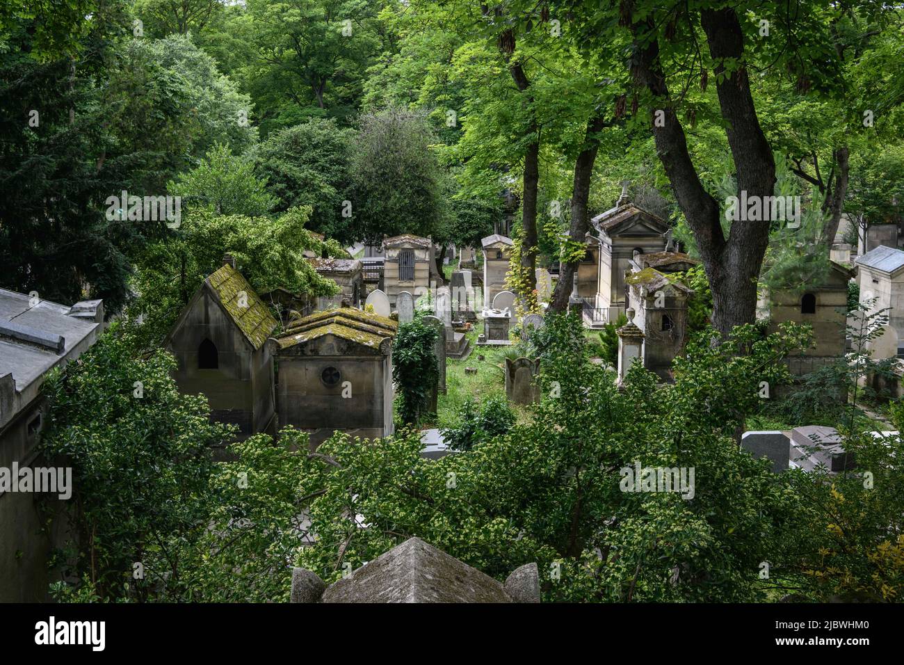 Francia, Parigi, 2021-07-07. Vista dall'alto di una vecchia parte del cimitero di Père Lachaise. Le tombe e i mausolei sono avvolti da una rigogliosa vegetazione. Foto Stock