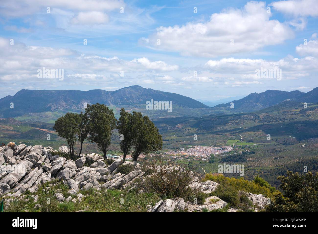 Vista sulle montagne e i campi della Sierra de las Nieves in Andalusia con il grazioso villaggio di El Burgo in lontananza Foto Stock