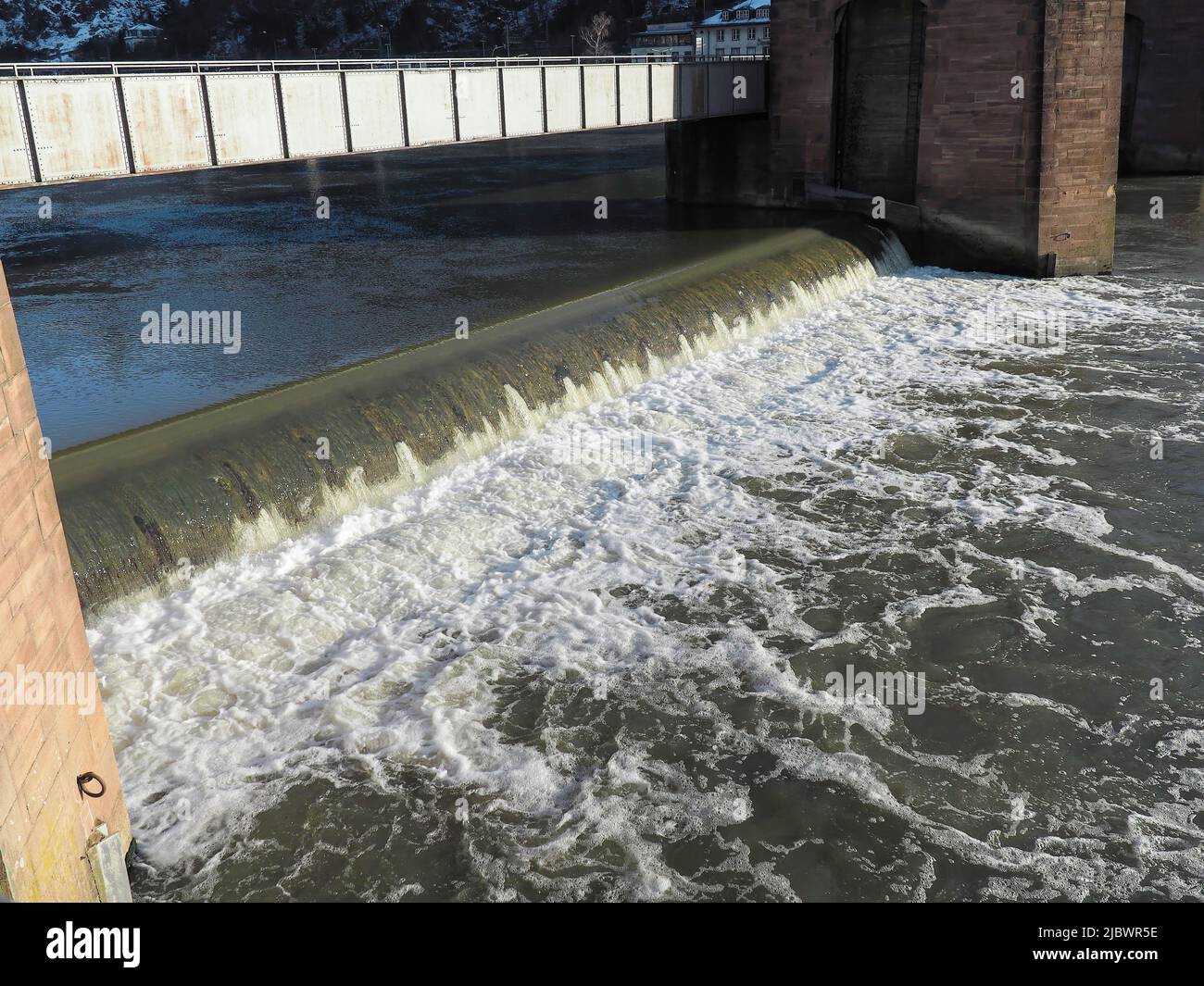 L'acqua scorre su una diga a bassa prevalenza nel centro storico di Heidellerg, in Germania Foto Stock