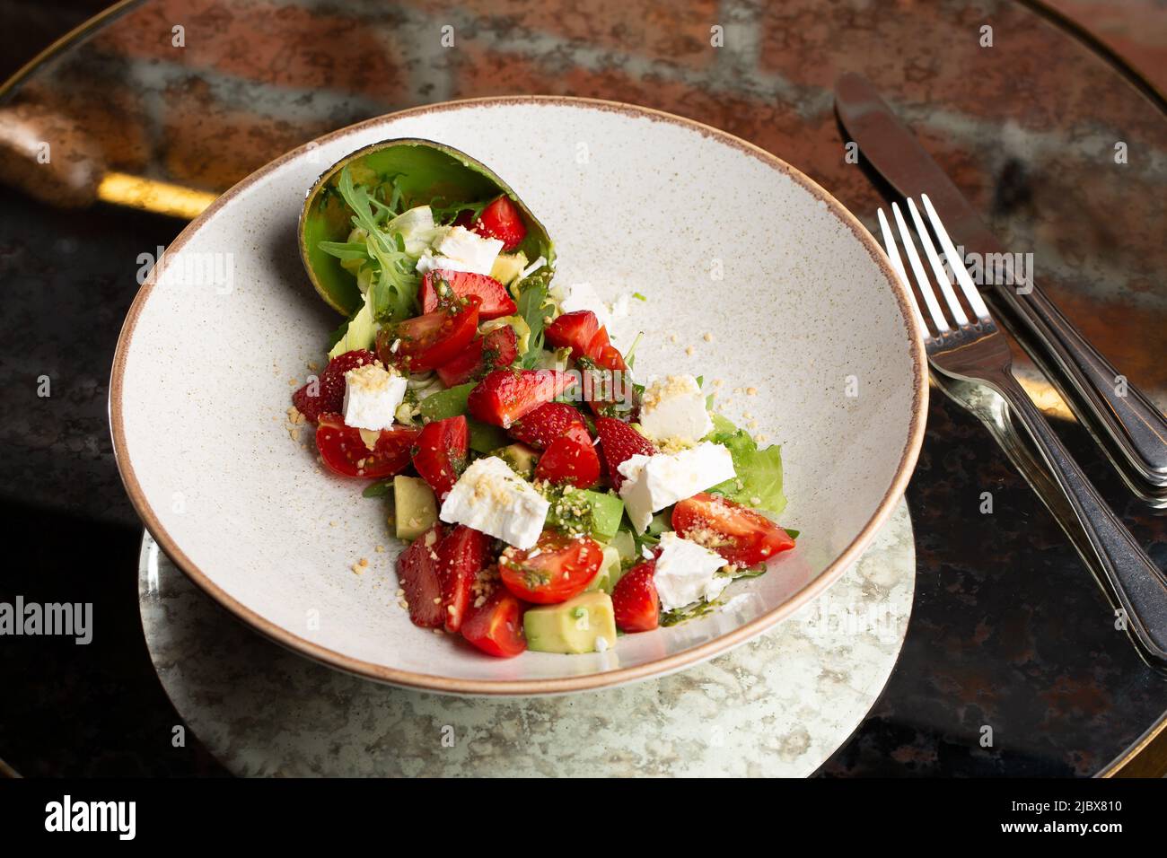 Insalata gustosa e sana con rucola, formaggio brie, avocado, pomodori ciliegini e fragole. Vista dall'alto. La disposizione piatta. Banner. Foto Stock