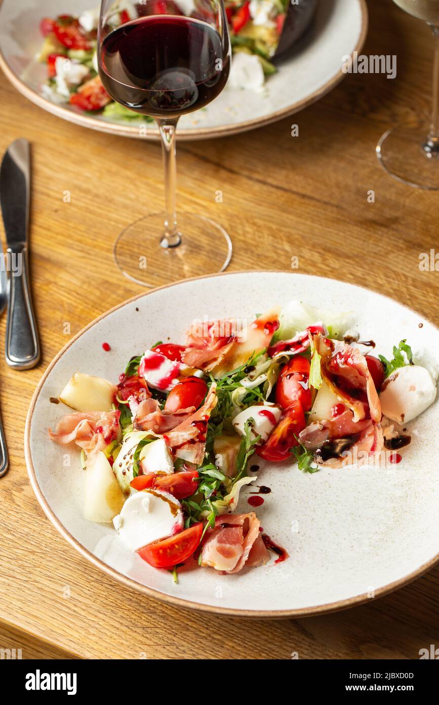 Insalata di prosciutto crudo con mozzarella e rucola su un piatto. Sfondo luminoso. Vista dall'alto. Spazio di copia. Foto Stock