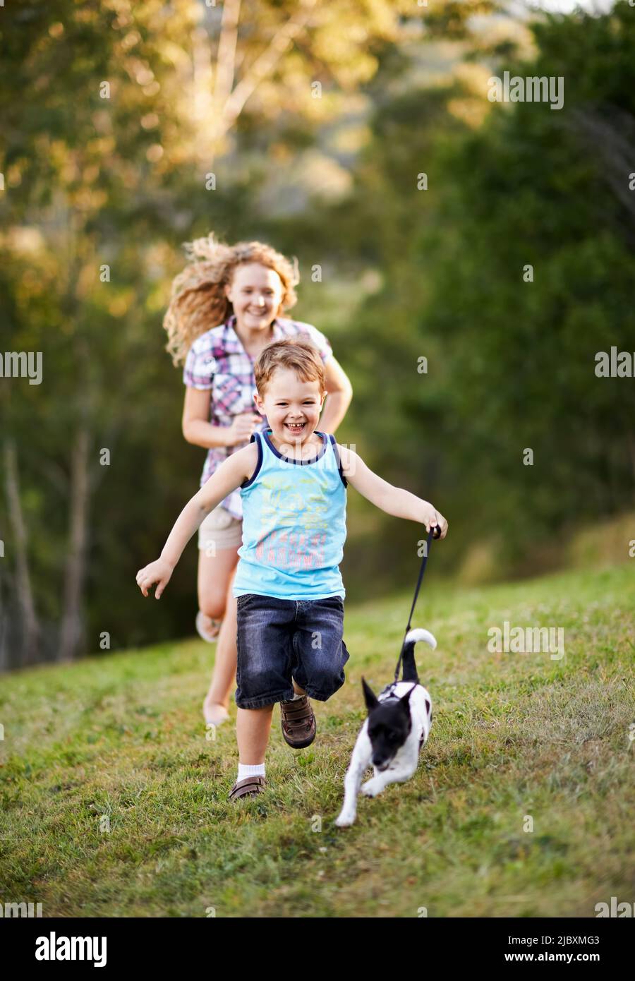 I bambini e il piccolo cane corrono e ridono Foto Stock