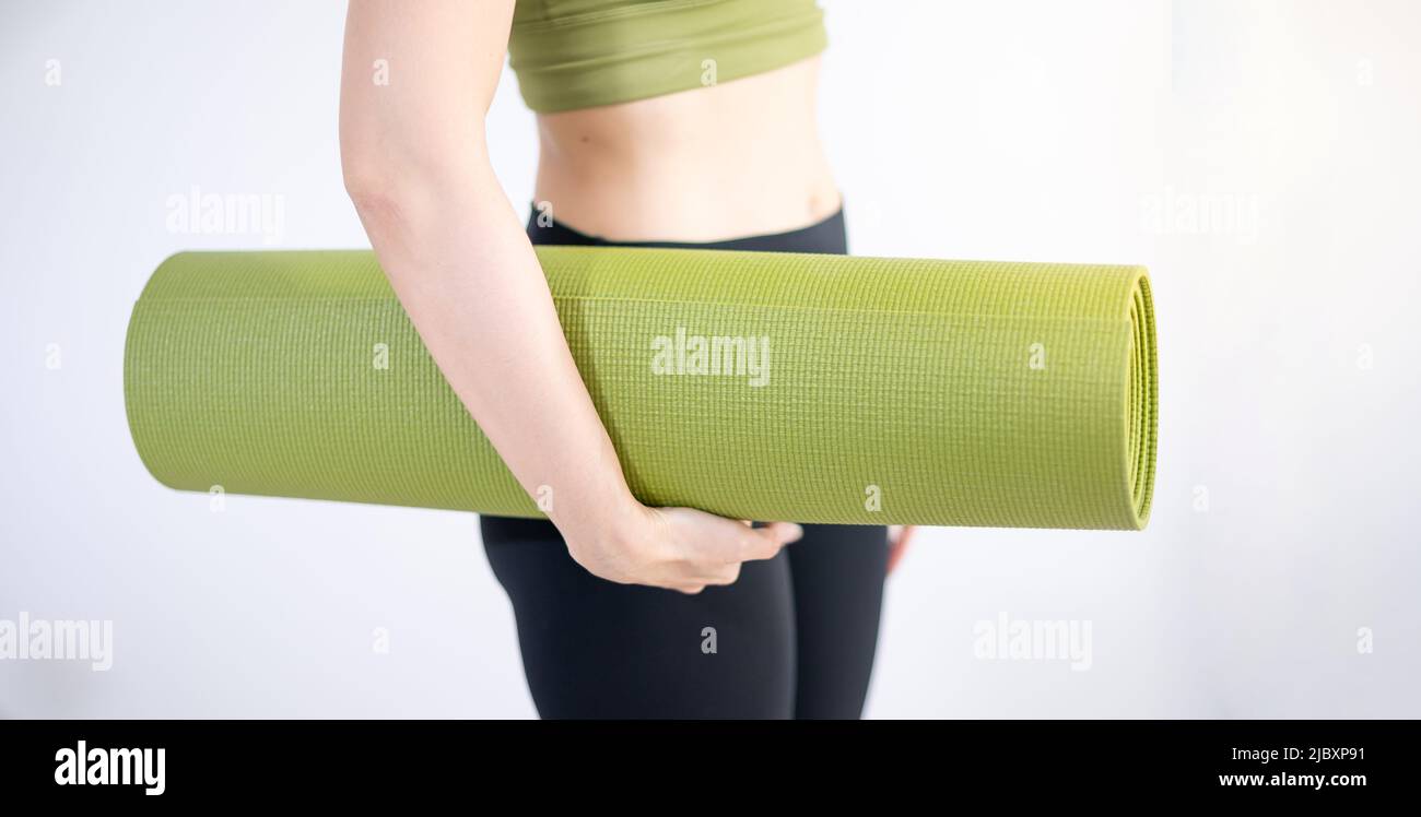 Mat yoga verde con mano femminile per preparare l'esercizio sul mat. Foto Stock