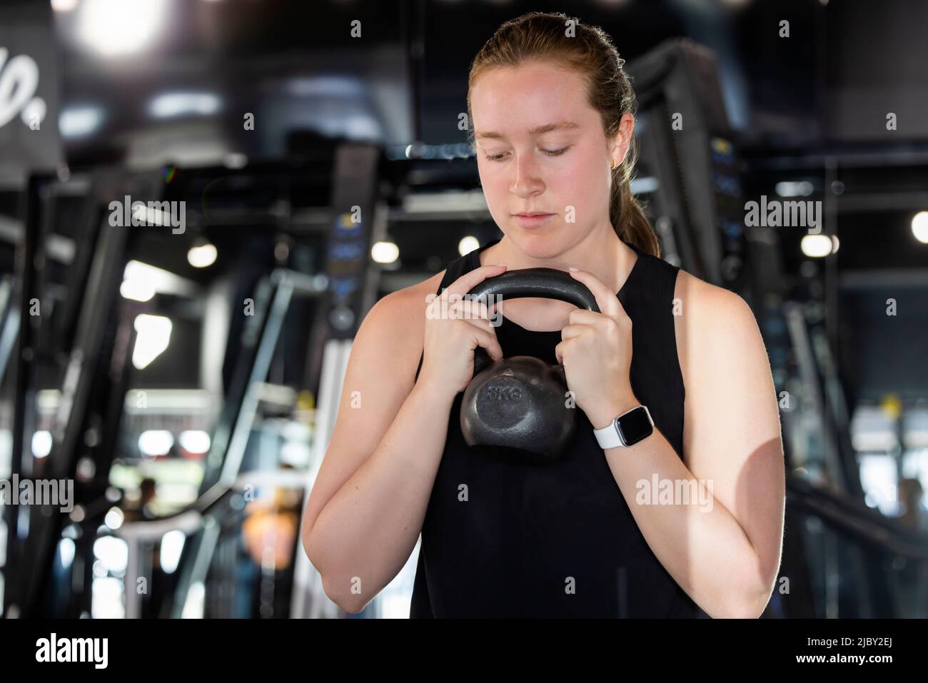 Donna in palestra tenendo manubri facendo squats Foto Stock