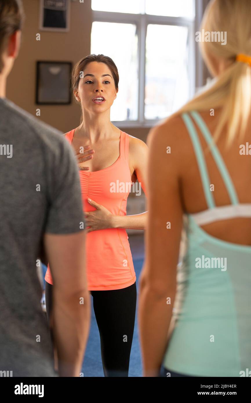 Un istruttore di fitness che parla di respirare agli studenti mentre sono in palestra Foto Stock