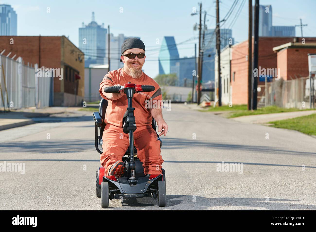 Ritratto di nano maschile in strada in Texas a bordo di uno scooter per la mobilità, fumare una sigaretta Foto Stock