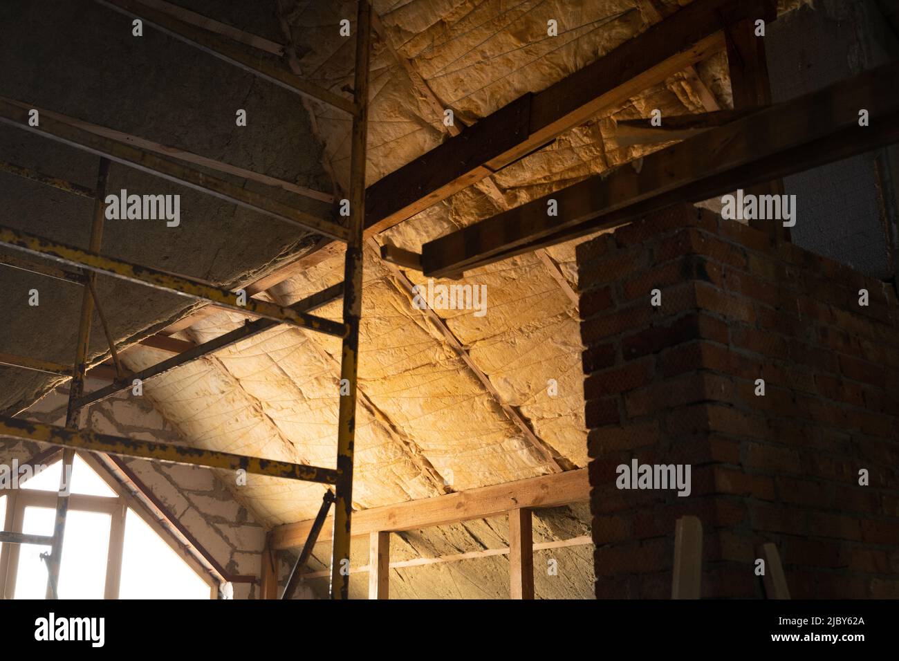 Il tetto di forma complessa è isolato con lana di vetro gialla e lana minerale verde. Tecnologia di isolamento del tetto. Ponteggi. Foto Stock