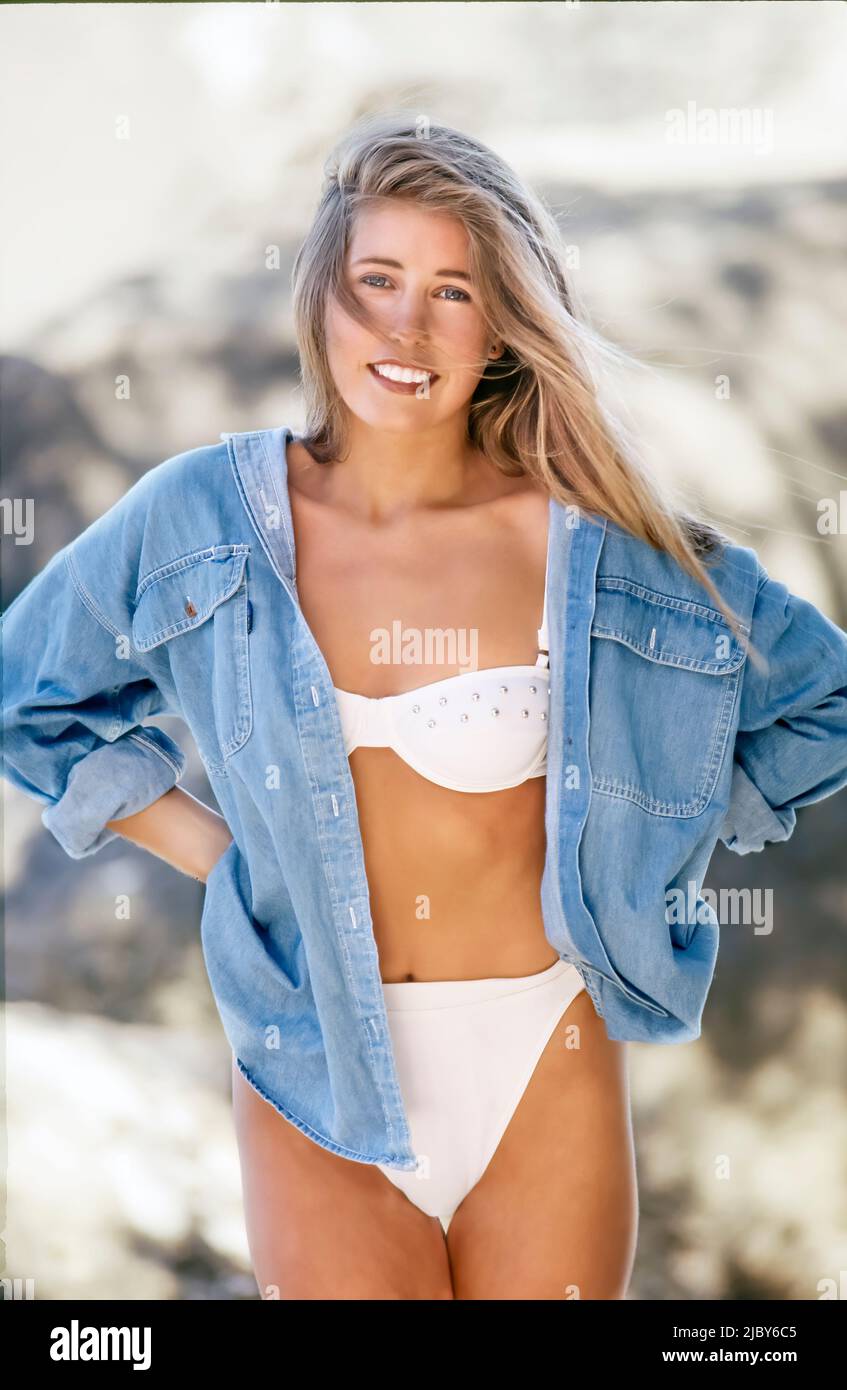 Giovane donna con top bikini bianco e giacca in denim in spiaggia e  sorridente Foto stock - Alamy