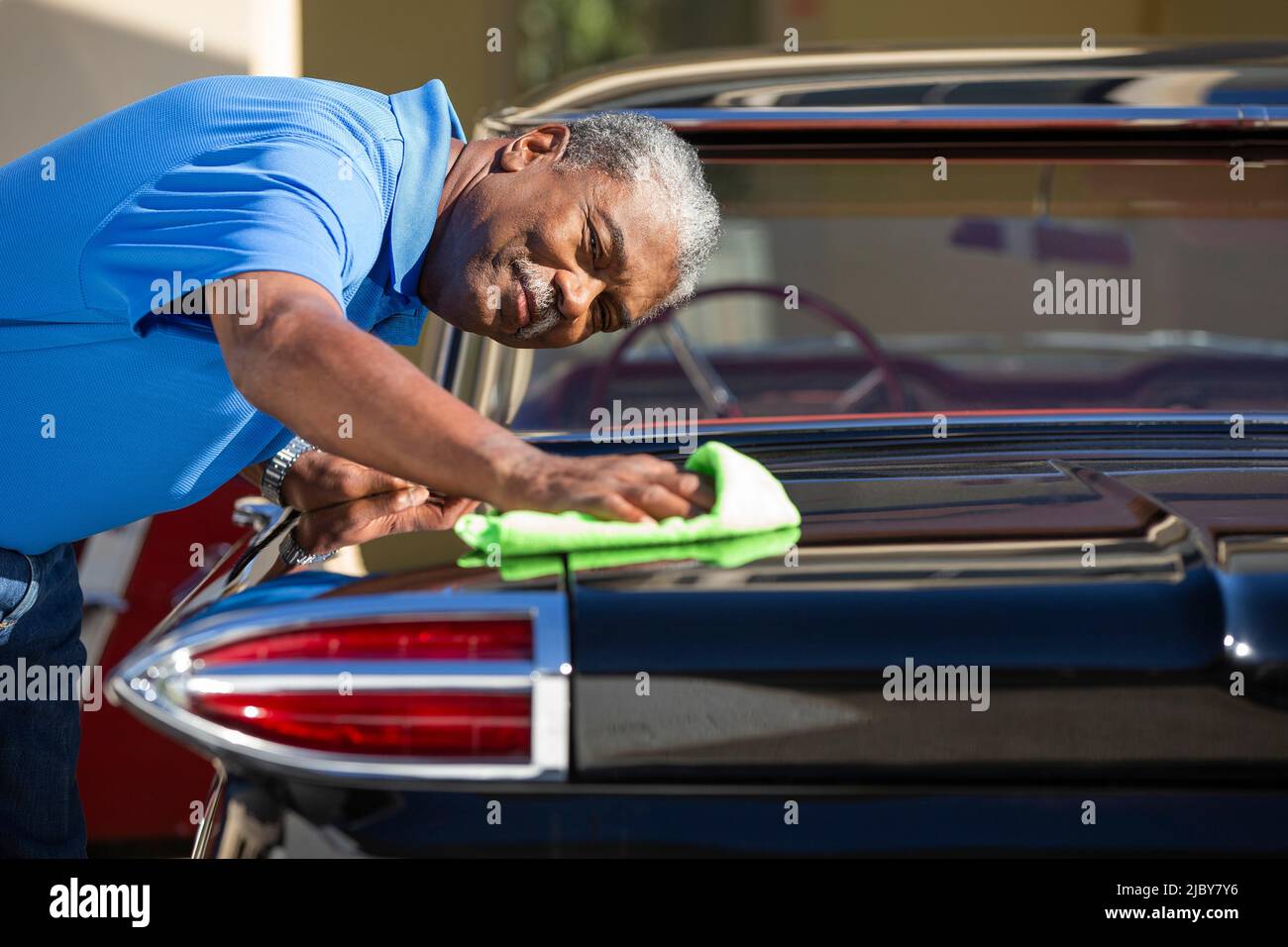 Uomo anziano che asciuga fuori vecchia automobile classica. Foto Stock