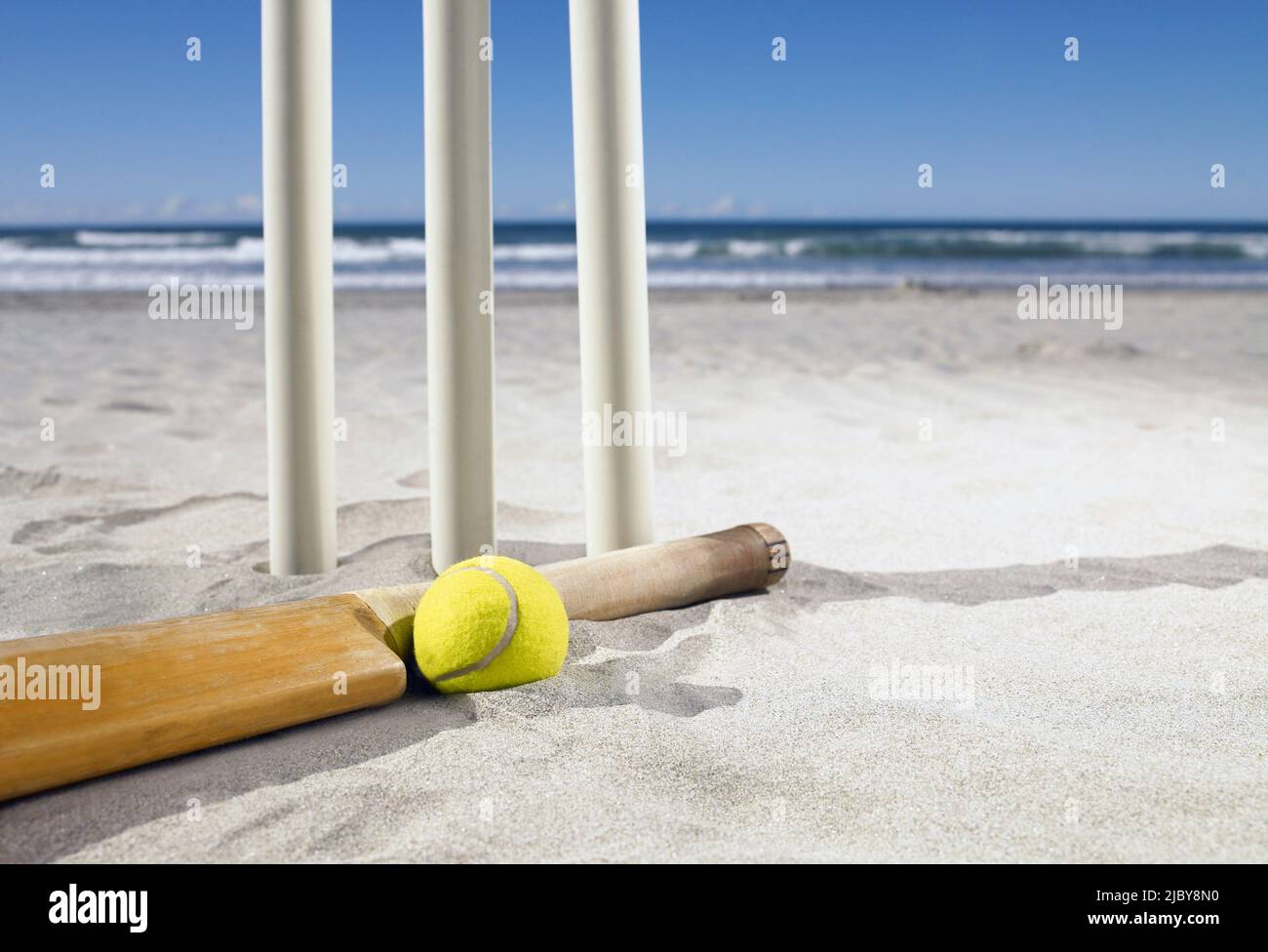 Pipistrello e palla che si stendono accanto a grumi di cricket in spiaggia Foto Stock