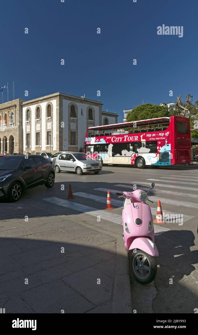 Vespa rosa scooter con tour bus in background, scena di strada, città di Rodi, isola di Rodi, Grecia, Dodecaneso Foto Stock