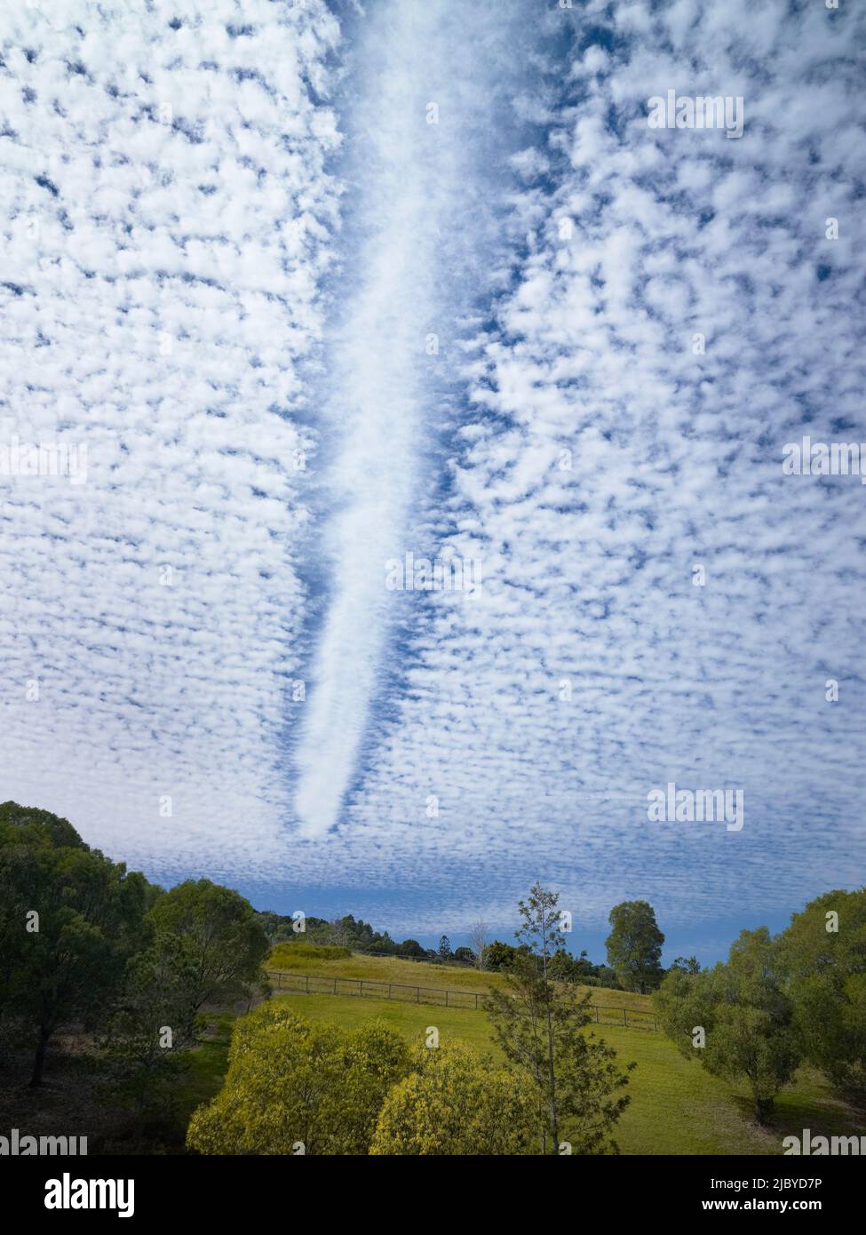 Jetstream dissipando percorso attraverso le nuvole fluffy sopra i terreni agricoli rurali Foto Stock