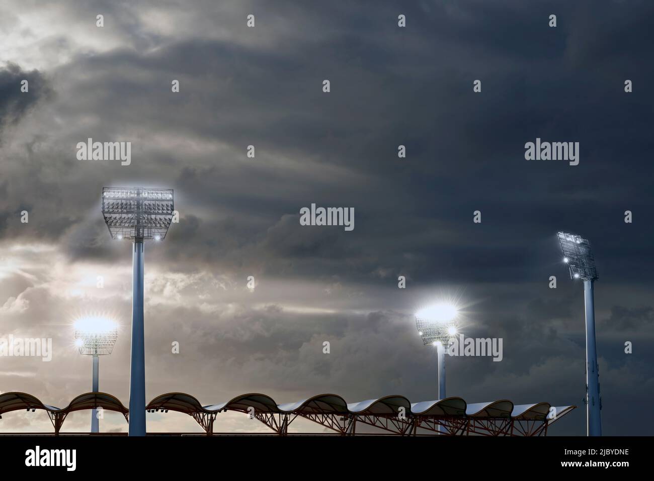 I riflettori si illuminano verso il Metricon Stadium in una serata nuvolosa Foto Stock